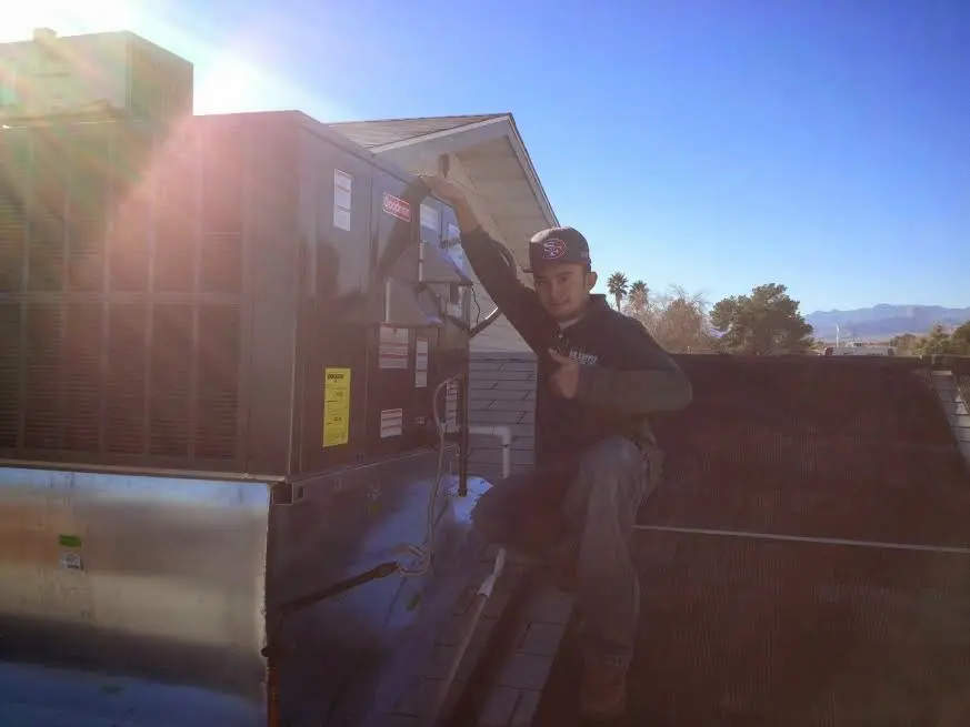 HVAC technician performing Air Duct Cleaning on a rooftop unit in Brookhaven